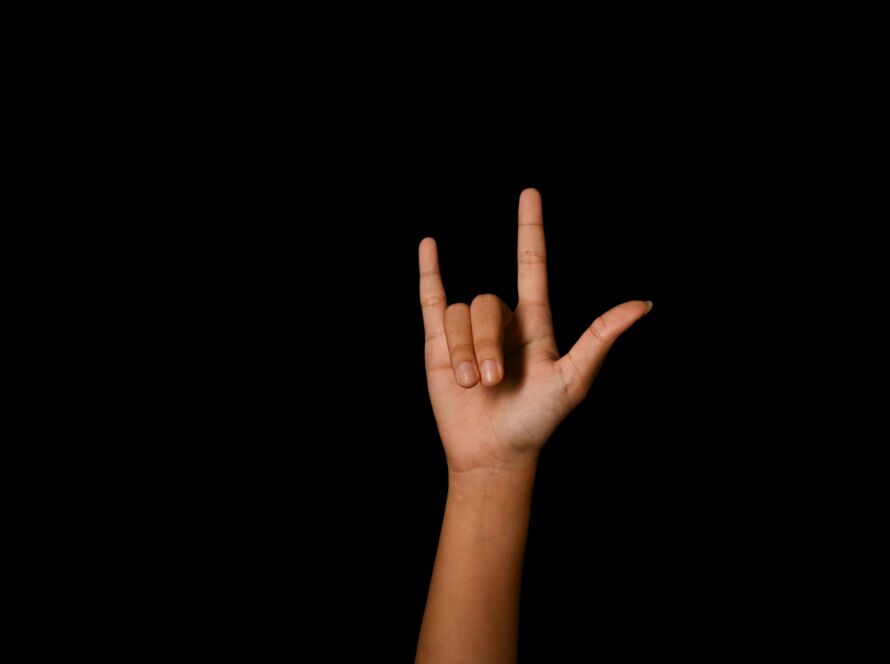 Hand showing I LOVE YOU in American sign language on black background.