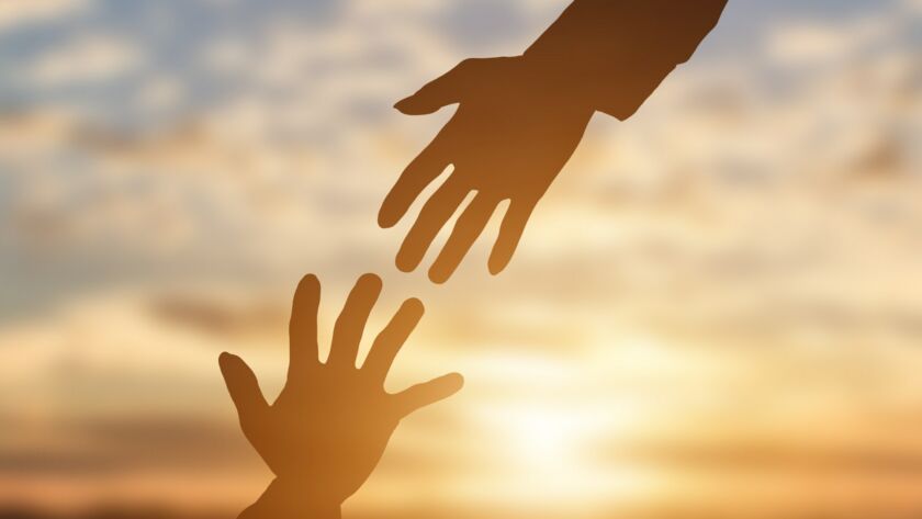 Silhouette of giving a helping hand, hope and support each other over sunset background.
