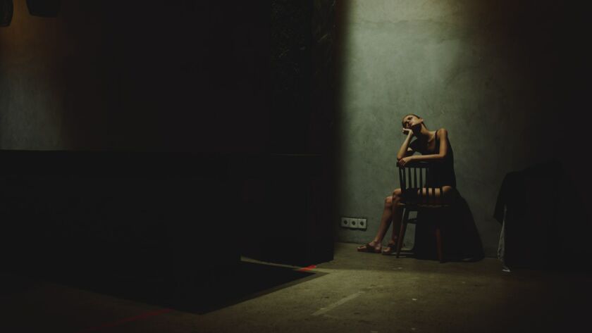 woman sitting on chairs in dark room loneliness conflict depression model interior